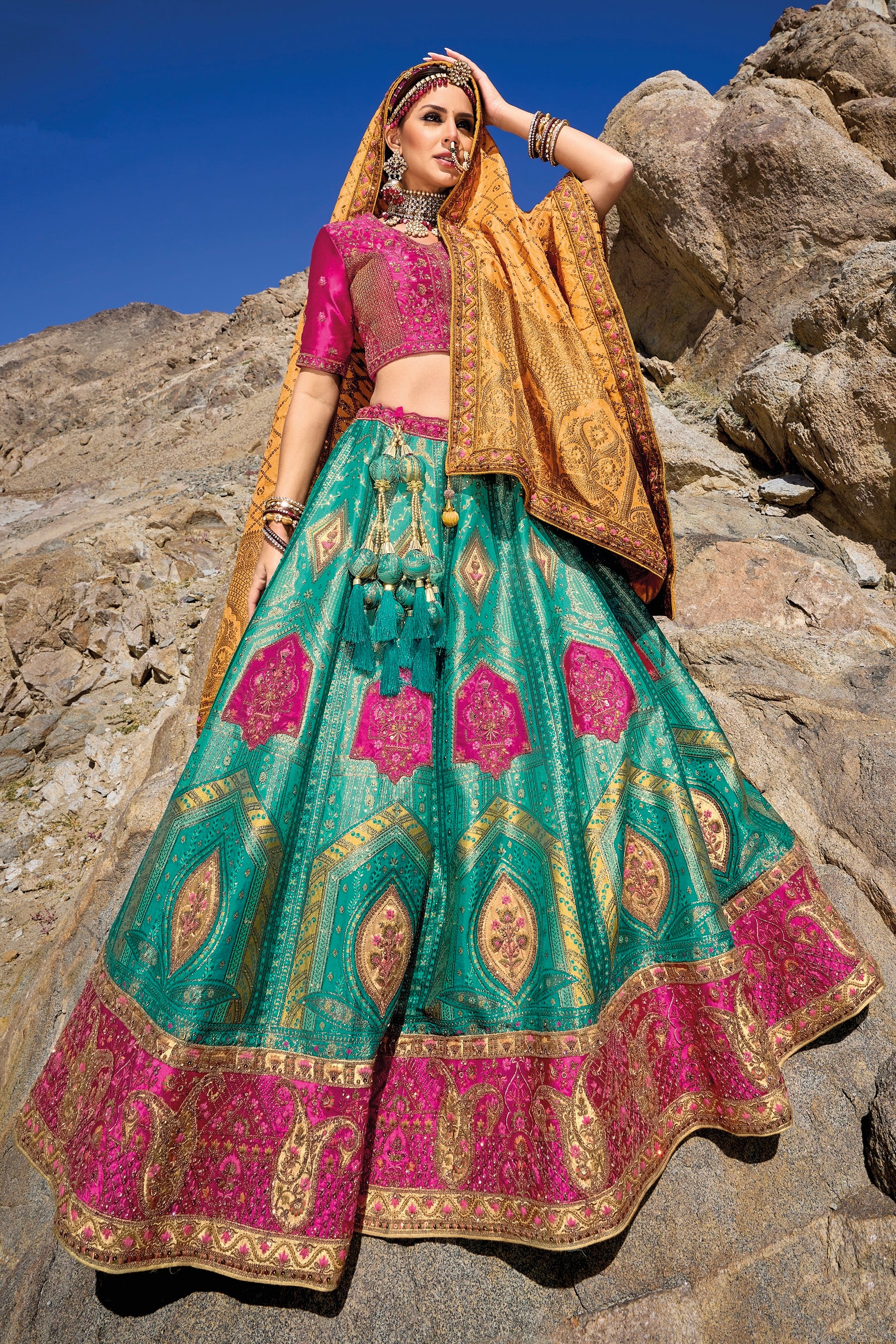 Woman in teal and pink Banarasi silk lehenga with embroidered blouse and yellow georgette dupatta.