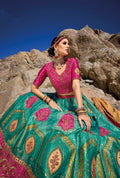 Woman in teal and pink Banarasi silk lehenga with embroidered blouse and yellow georgette dupatta.