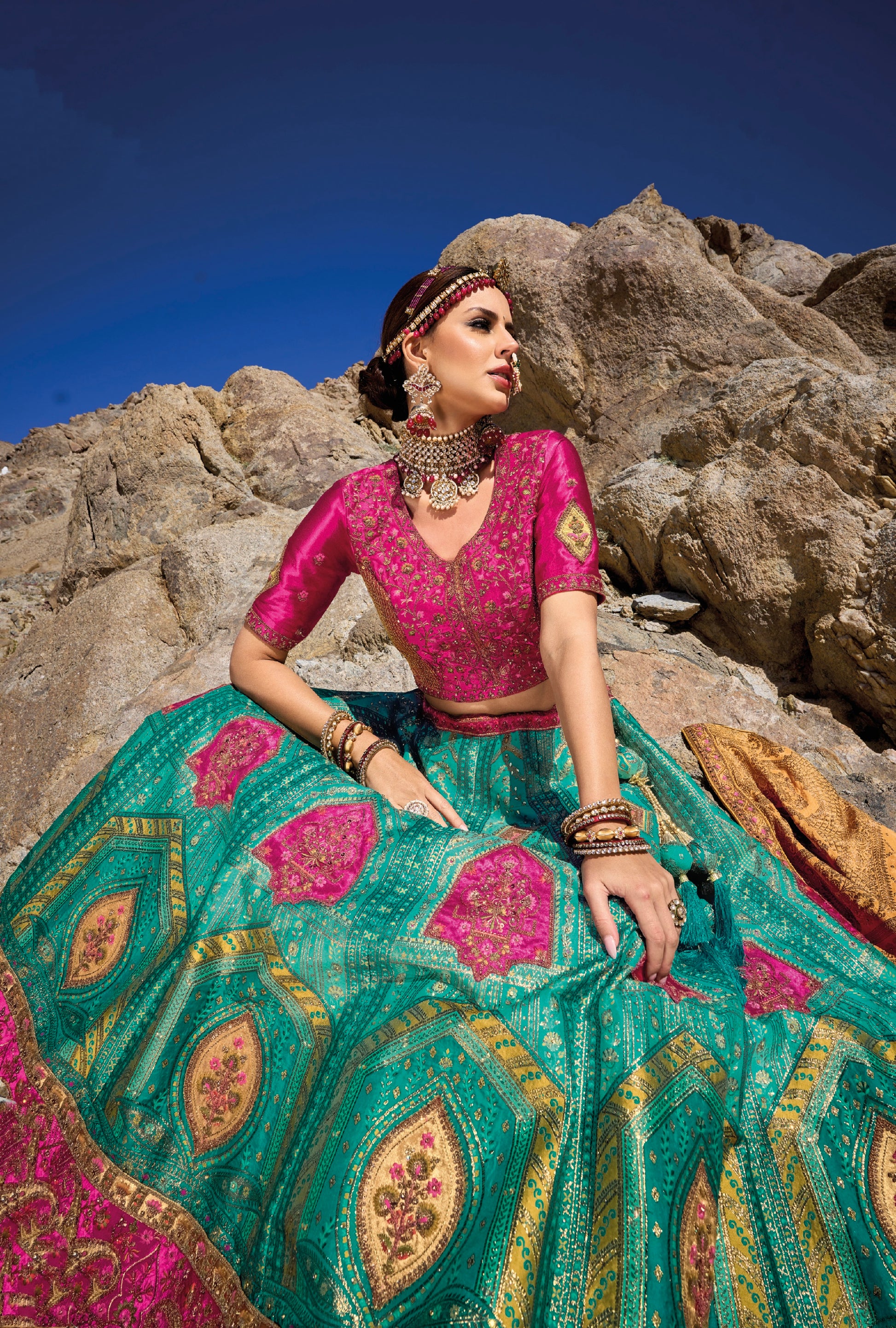 Woman in teal and pink Banarasi silk lehenga with embroidered blouse and yellow georgette dupatta.