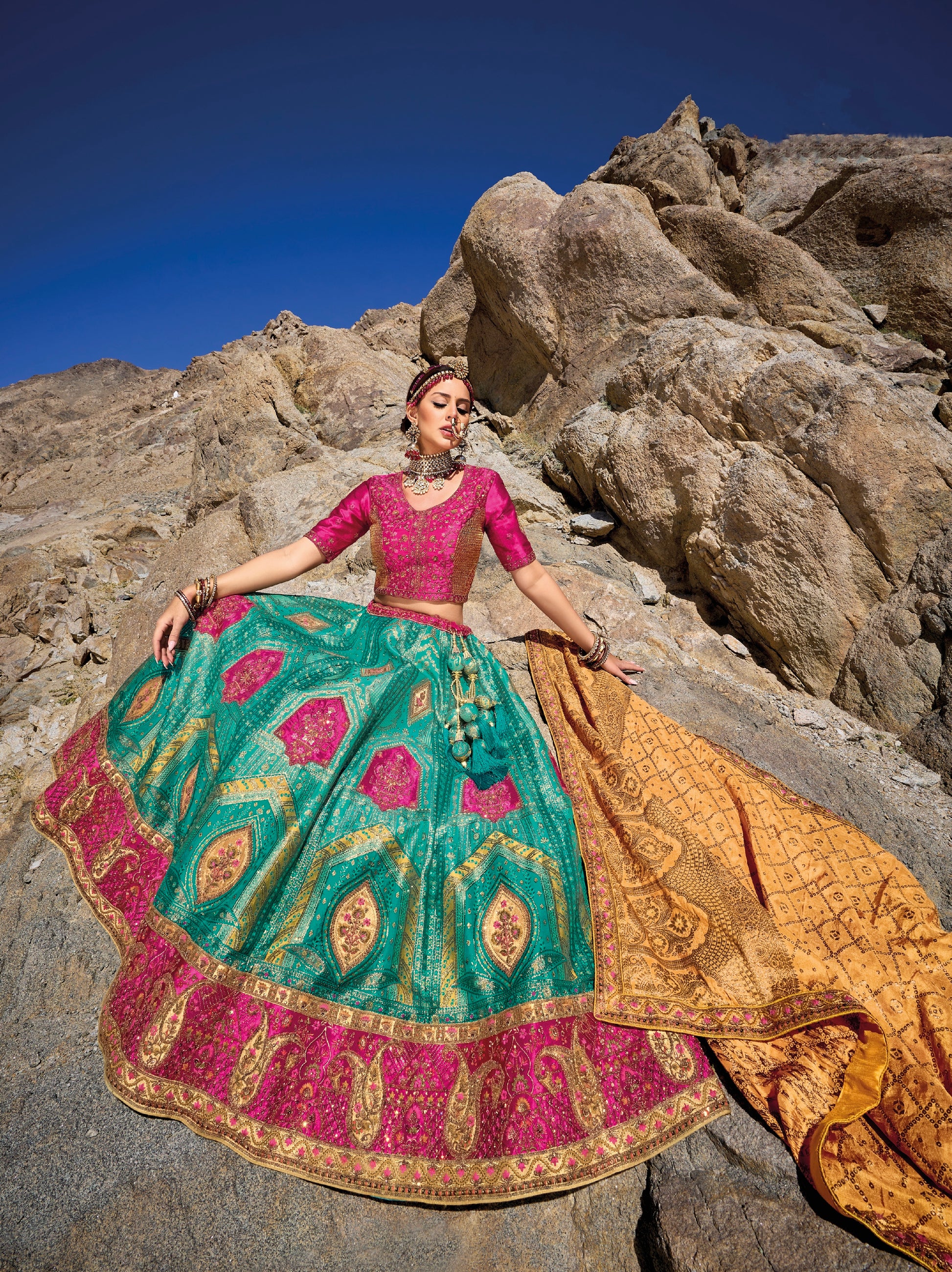 Woman in teal and pink Banarasi silk lehenga with embroidered blouse and yellow georgette dupatta.