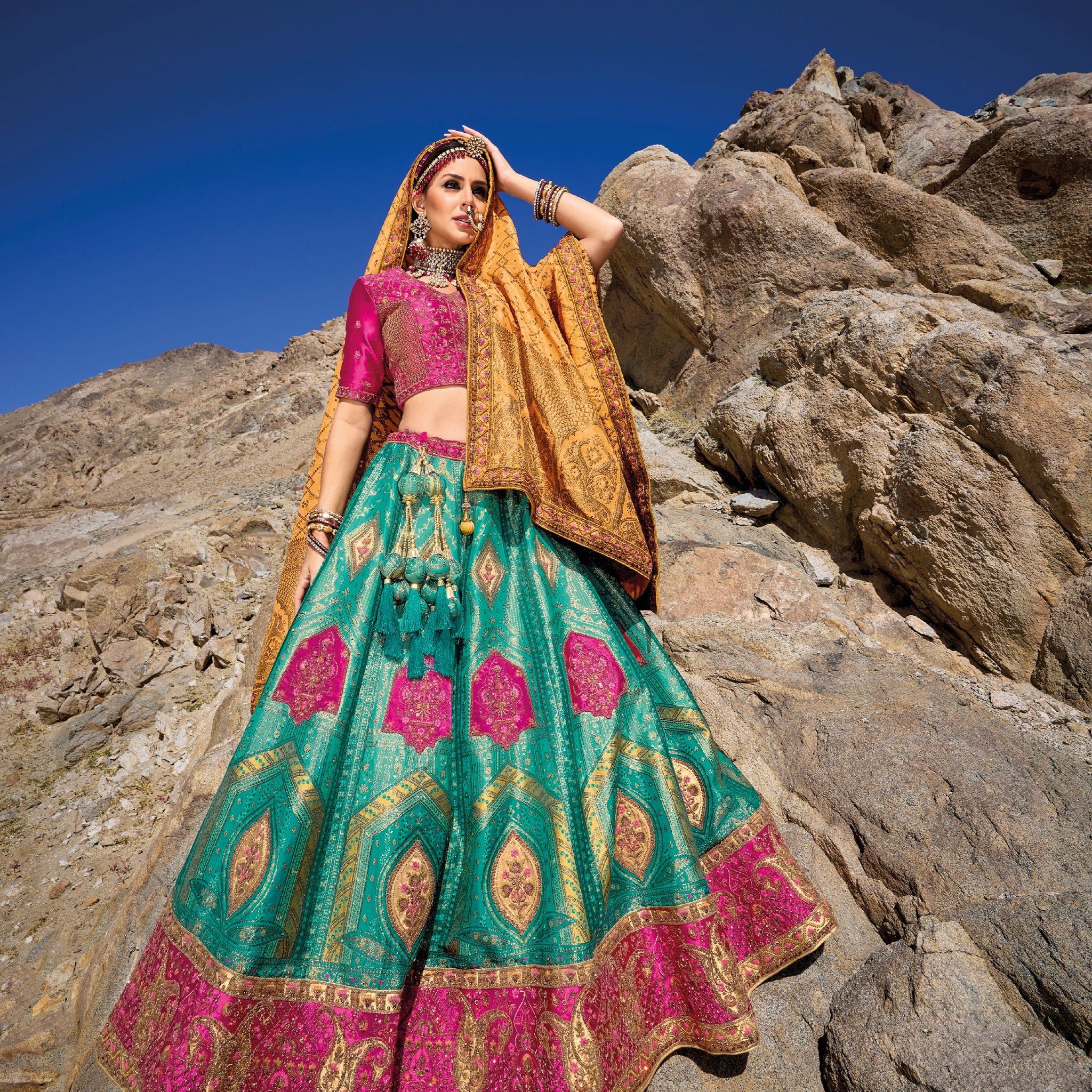 Woman in teal and pink Banarasi silk lehenga with embroidered blouse and yellow georgette dupatta.