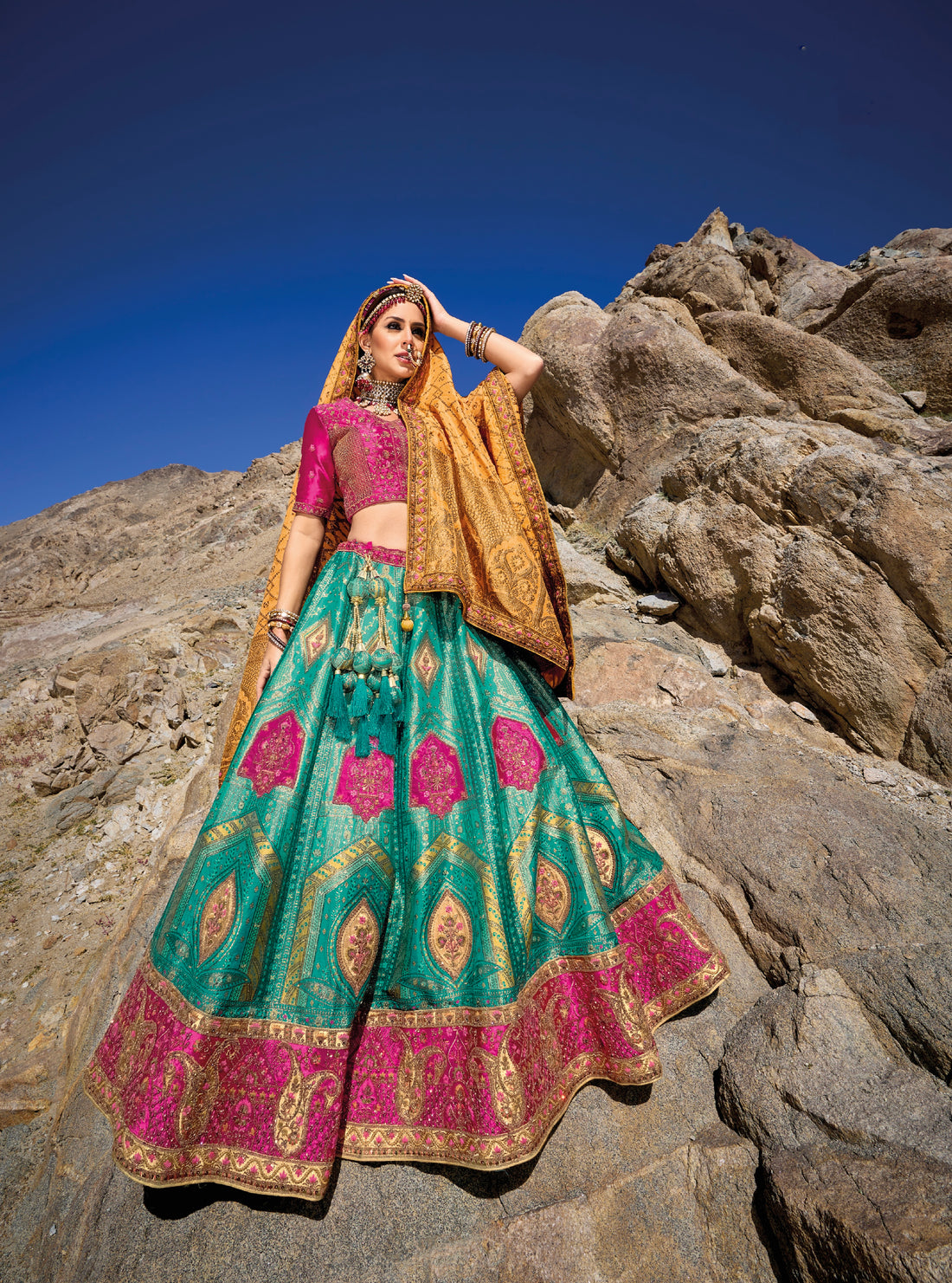 Woman in teal and pink Banarasi silk lehenga with embroidered blouse and yellow georgette dupatta.