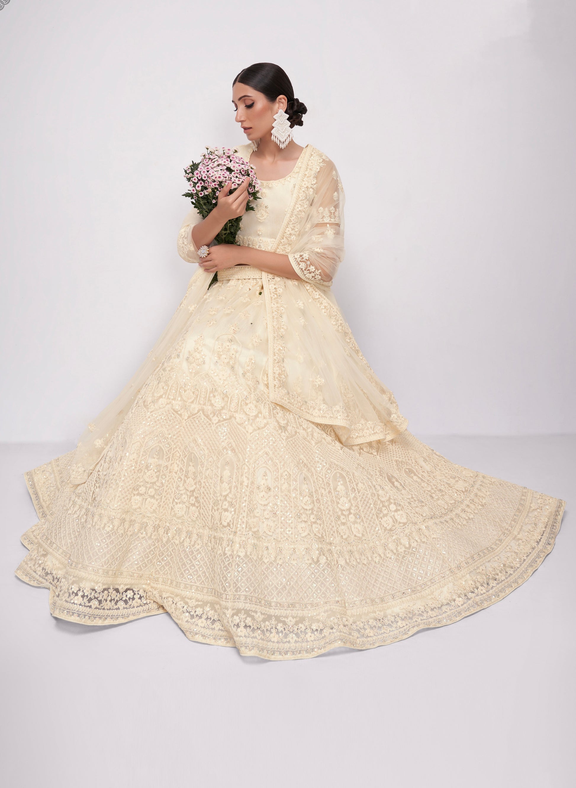 Elegant off-white net lehenga with intricate embroidery and stone embellishments.