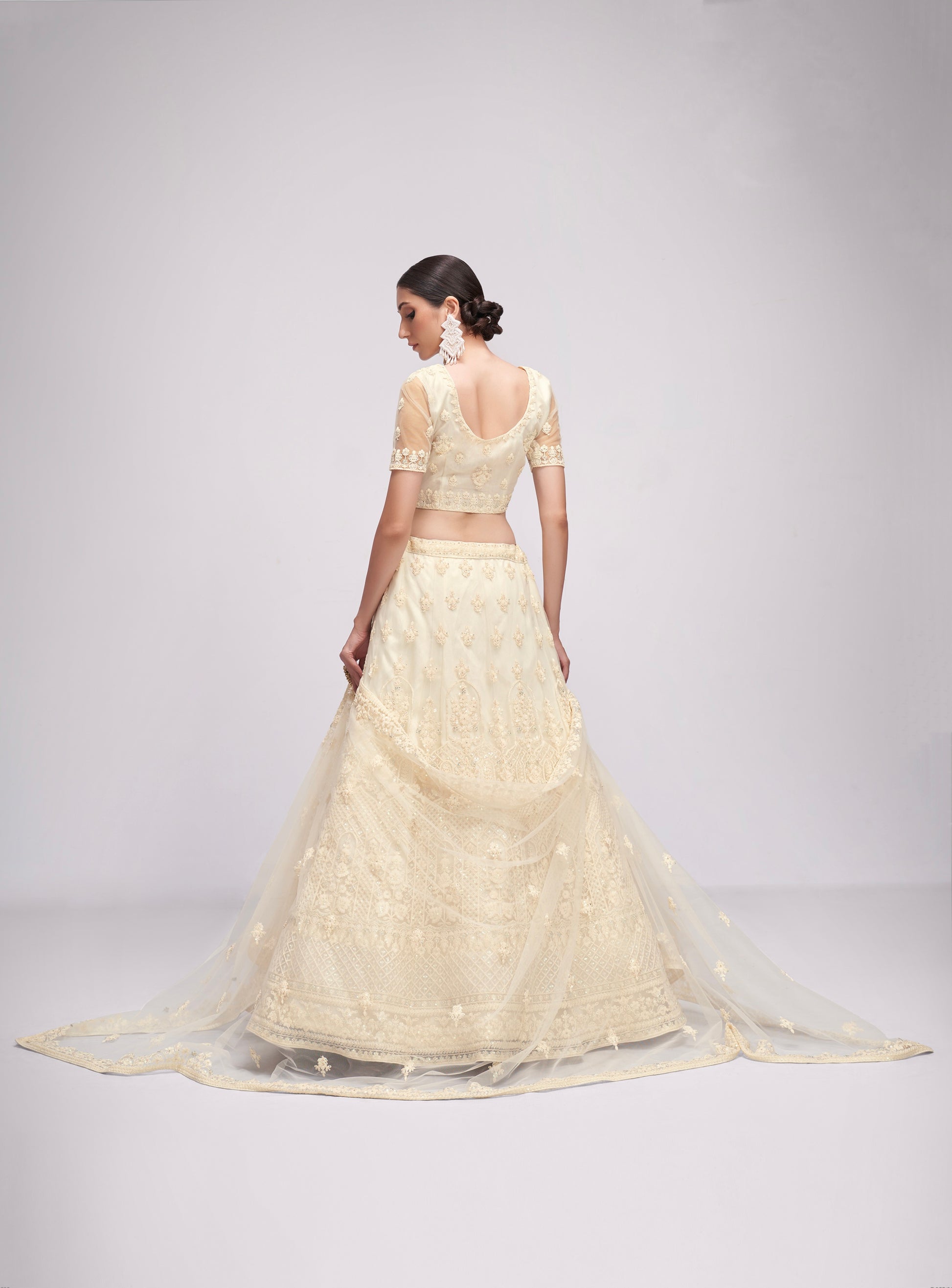 Elegant off-white net lehenga with intricate embroidery and stone embellishments.