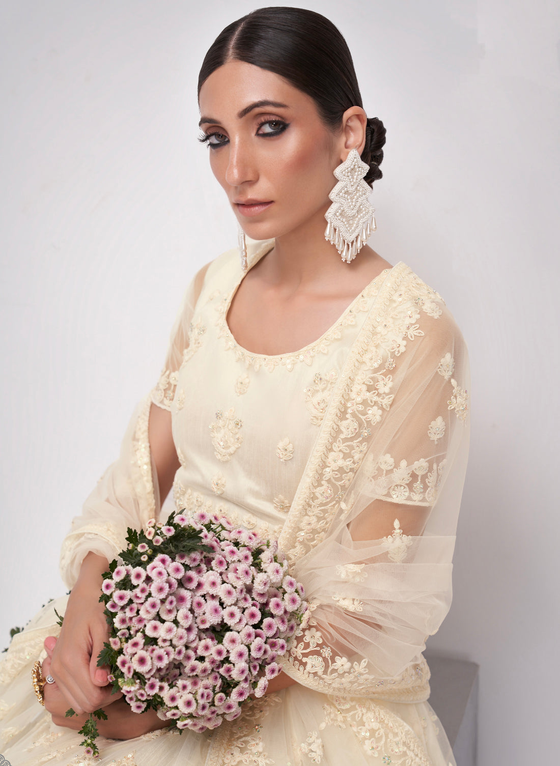 Elegant off-white net lehenga with intricate embroidery and stone embellishments.