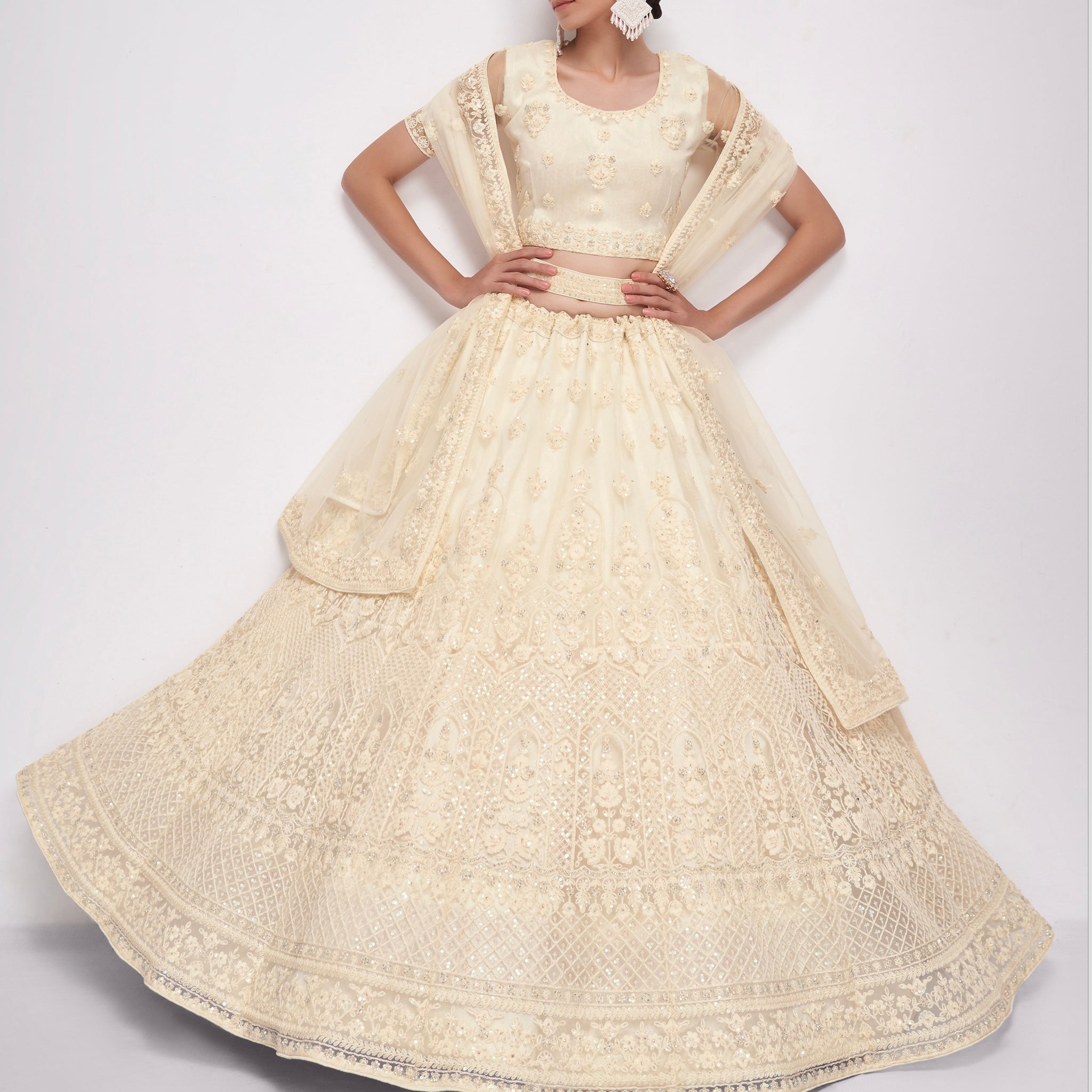 Elegant off-white net lehenga with intricate embroidery and stone embellishments.