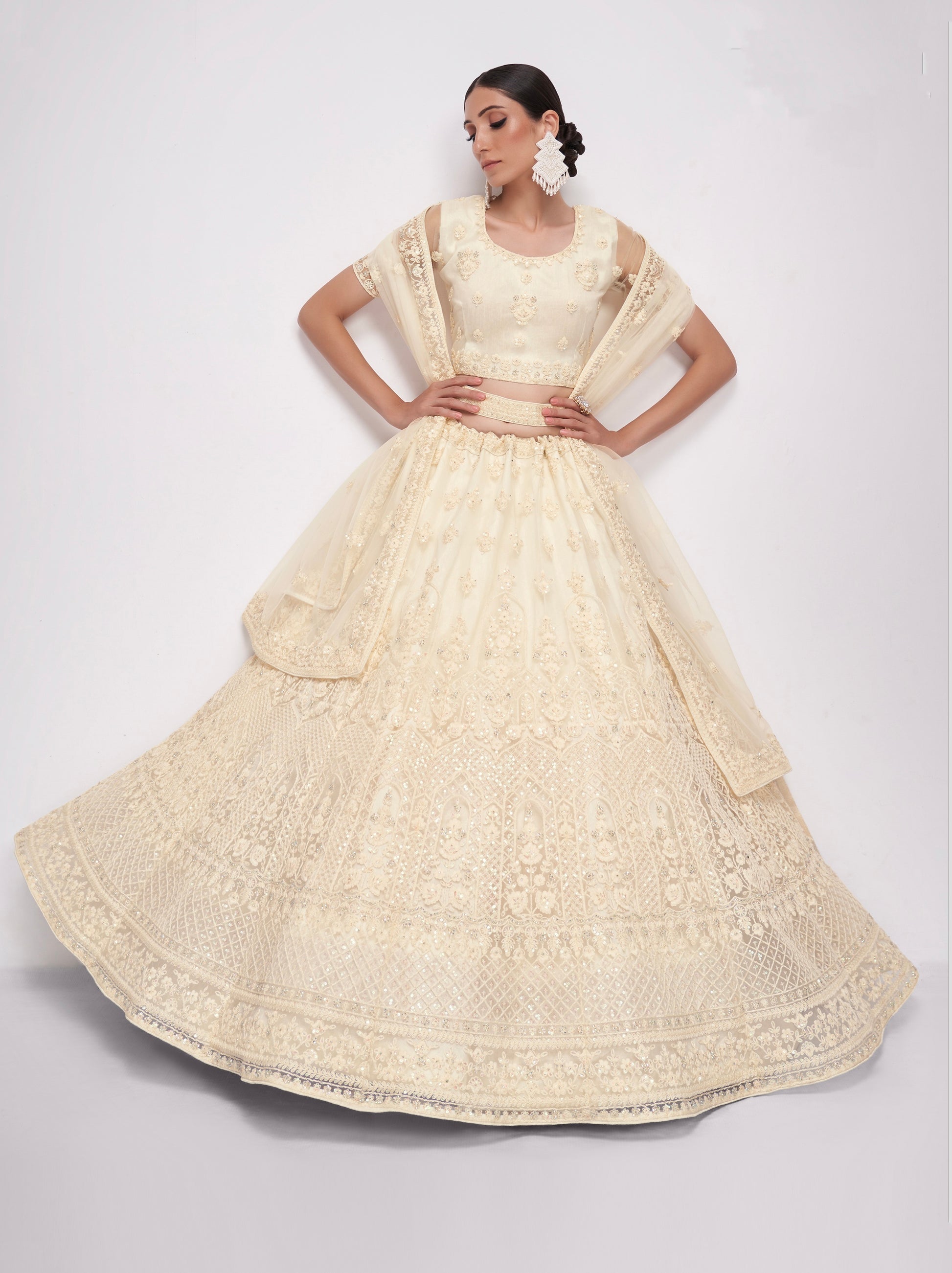 Elegant off-white net lehenga with intricate embroidery and stone embellishments.