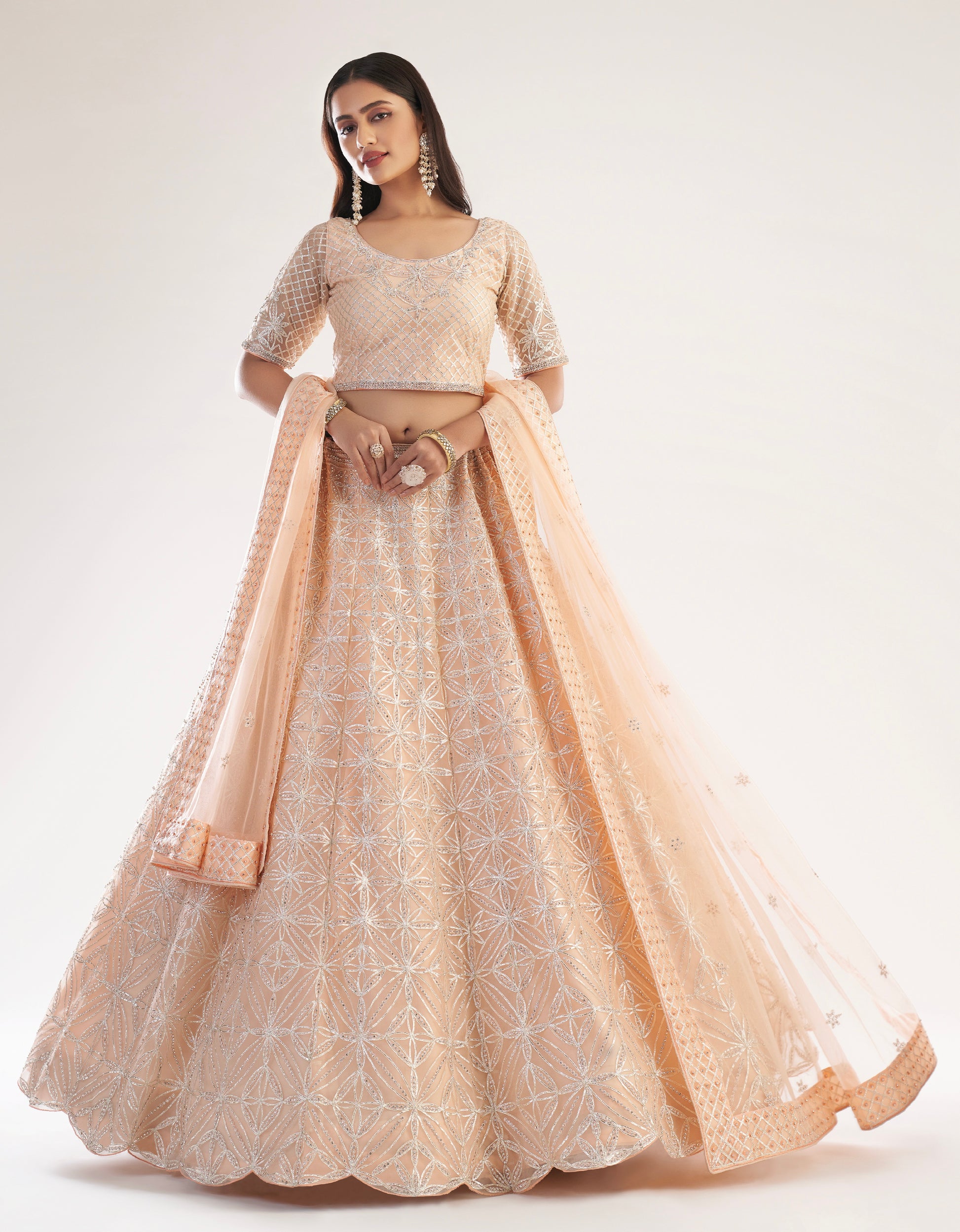 Elegant peach bridal lehenga with ribbon gota work and heavy zarkan embellishments.