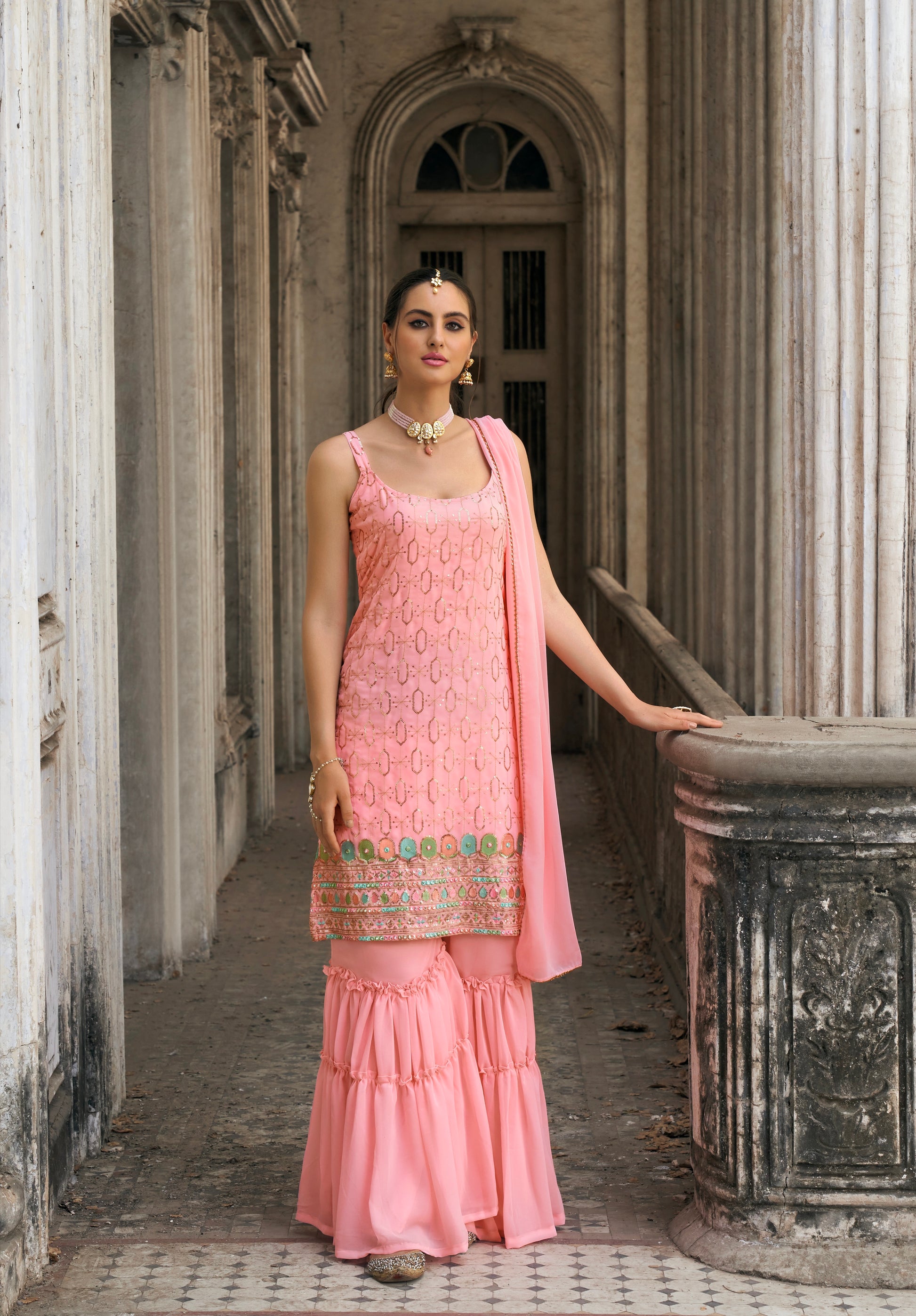 Woman in pink embroidered georgette sharara suit with dupatta.