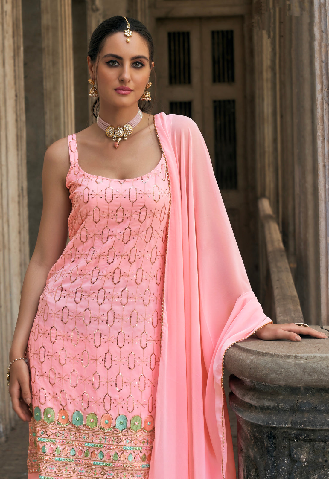 Woman in pink embroidered georgette sharara suit with dupatta.