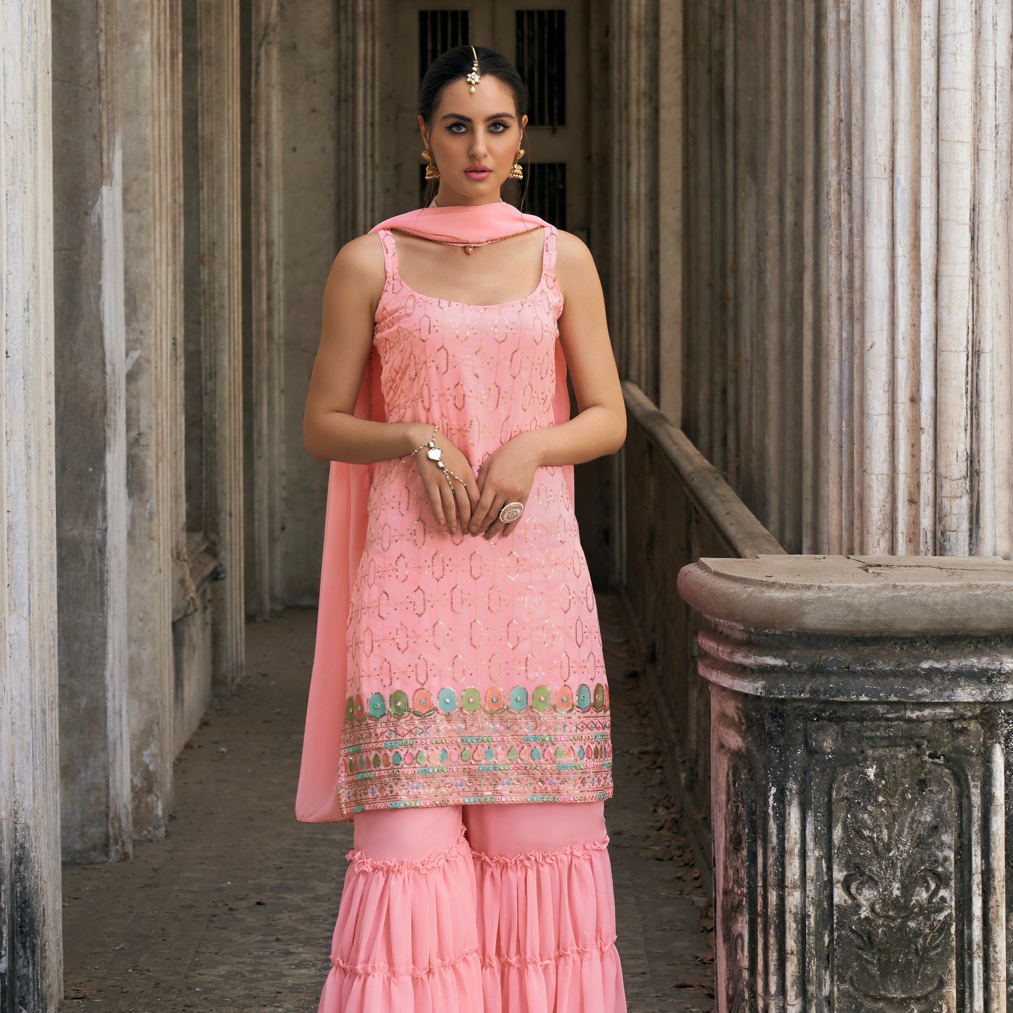 Woman in pink embroidered georgette sharara suit with dupatta.